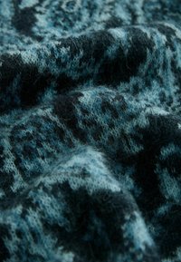 Strickstoff mit einer Mischung aus Dunkelblau, Hellblau und Schwarz, der eine weiche Textur und ein abstraktes Muster aufweist.