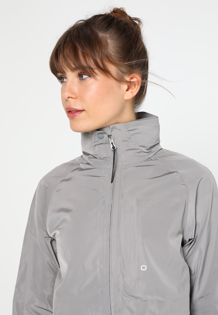 Hellgraue Zipjacke mit hohem Kragen, glatter Textur und kleinem Logo auf der Brust. Verfügt über einen schlanken Schnitt und minimalistisches Design.