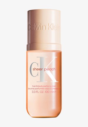 Flacon de parfum brume cheveux et corps Calvin Klein Sheer Peach, 100 ml, avec un bouchon couleur pêche et un liquide pêche translucide à l’intérieur.