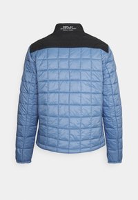 Giacca in nylon trapuntato azzurro chiaro con yoke e colletto neri, con la scritta "REPLAY RECYCLED NYLON JACKET" sul colletto posteriore.