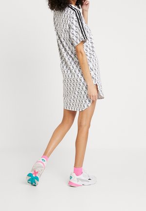 Robe à manches courtes avec un motif géométrique en noir et blanc, agrémentée de bandes latérales noires. Associée à des baskets blanches et des chaussettes roses.