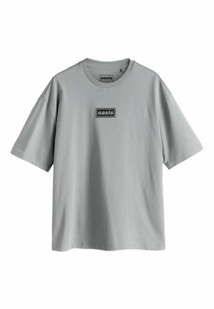 Grå kortärmad t-shirt av bomull, med rund halsringning och ett rektangulärt svart logotypmärke med texten "oasis" på framsidan.