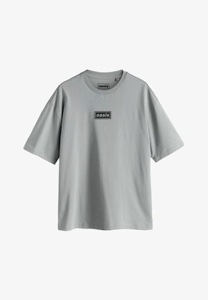 Szara bawełniana koszulka z krótkim rękawem, z okrągłym dekoltem i prostokątną czarną naszywką z napisem "oasis" na przodzie.