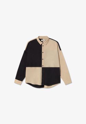 Camicia con bottoni caratterizzata da un design a patchwork, con sezioni beige e nere, maniche lunghe e colletto a punta. Texture liscia con bottoni.