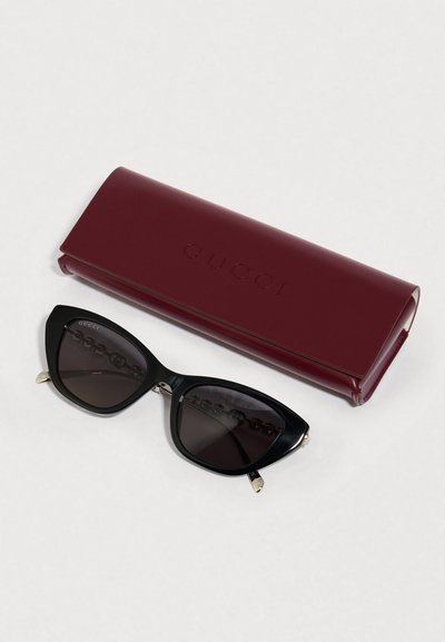 Melni kaķacs acu saulesbrilles ar gradienta tumšiem stikliem, sudraba akcentiem; komplektā ar buržuānas cietu futlāri ar uzrakstu "Gucci".