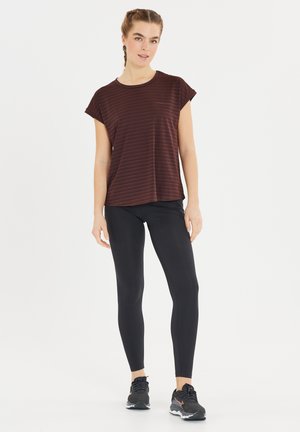 Haut à manches courtes rayé bordeaux associé à un legging noir et des chaussures de sport noires. Le haut présente une coupe décontractée et une texture douce.