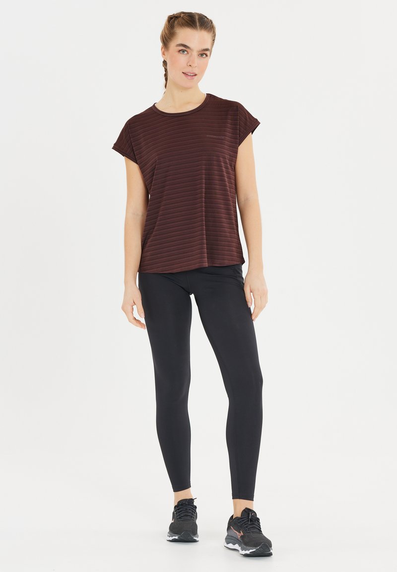 Bordeaux gestreepte top met korte mouwen, gecombineerd met zwarte leggings en zwarte sportschoenen. De top heeft een relaxte pasvorm en een zachte textuur.