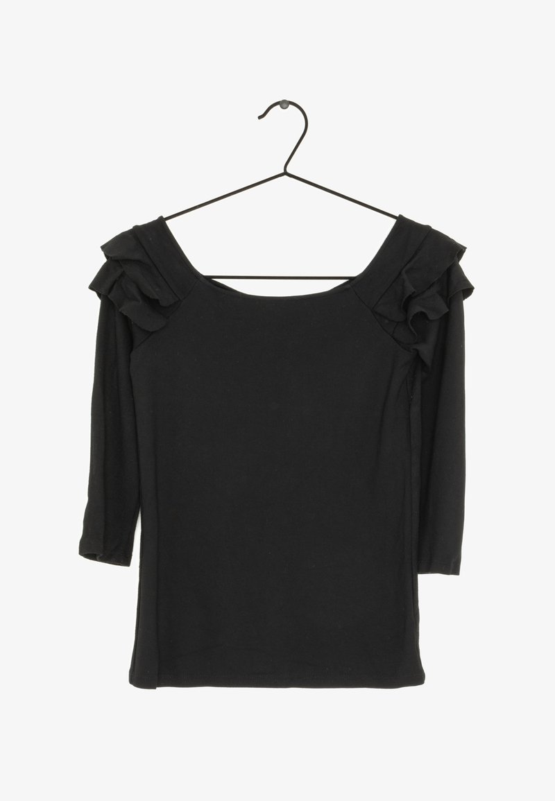 Blouse noire à manches longues avec détails froncés aux épaules, suspendue à un cintre en fil noir sur fond blanc.