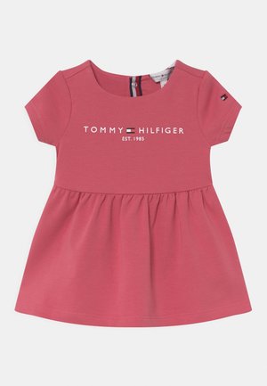 Kortärmad, rosa bomulls klänning med en volangkjol, med en vit tryckt logotyp "TOMMY HILFIGER EST. 1985" över bröstet.