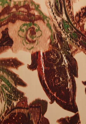 Tessuto con un design floreale che presenta colori verde scuro, marrone e crema. Il motivo include foglie intricate e dettagli di fiori.