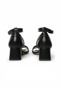 Sandali neri con tacco a rocchetto, dotati di cinturini regolabili alla caviglia, in pelle liscia, con tacco quadrato e design open-toe che presenta più cinturini sottili.