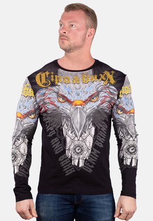 Camisa de manga larga negra con gráfico de águila en gris y azul, acentuada con texto y patrones dorados, que cuenta con un diseño ajustado y un cuello redondo.