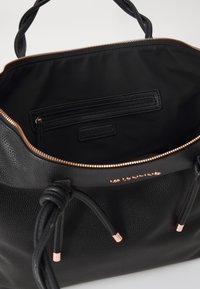Black leather handbag with textured exterior, zipper closure, and rose gold hardware. Interior features a zippered pocket and smooth lining.