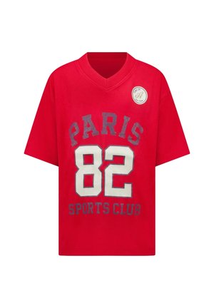 Rode t-shirt met korte mouwen en een V-hals, met "PARIS 82 SPORTS CLUB" in grijs en wit gedrukt, plus een ronde patch op de schouder.