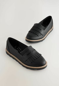 Mocassins noirs avec une tige en cuir texturé, des détails à franges et une semelle contrastante en marron clair. Bout rond, design plat, semelle intérieure à motifs.