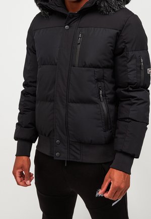 Black puffer jacket with a detachable fur-lined hood, multiple zipped pockets, ribbed cuffs, and a button front closure.