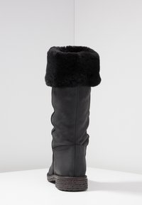 Botte noire haute en cuir, dotée d'un col en fourrure noire pelucheuse, d'une semelle texturée et d'un discret design froncé sur le tige.