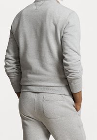 Grå bomullströja med ribbad mudd och fåll, med rund halsringning och en slät yta, ihop med matchande sweatpants.