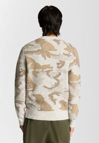 Grauer Pullover mit einem beigen Camouflage-Muster, gestrickte Textur, Rundhalsausschnitt und gerippte Ärmelbündchen sowie Saum, getragen mit olivgrünen Hosen.