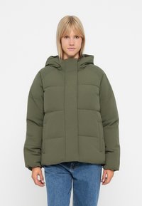 Chaqueta acolchada en verde oliva con cierre de cremallera en el frente, capucha ajustable y dos bolsillos frontales. Fabricada en un material suave y texturizado.