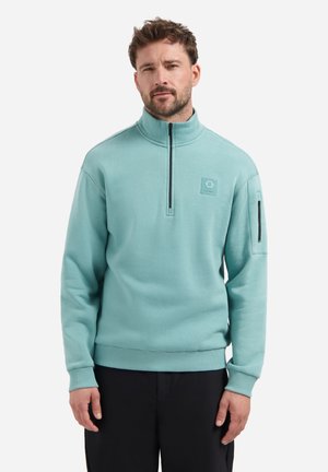 Hellblau-grüner Zip-Kragen-Sweatshirt aus weichem Stoff, mit einem Brustlogo-Patch und einer seitlichen Reißverschlusstasche, ausgestattet mit gerippten Bündchen und Saum.