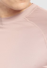Helles pinkes Sportshirt mit glatter, strukturierter Oberfläche; verfügt über einen hohen Halsausschnitt und Nähte an den Schultern.