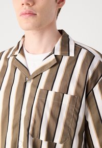 Brun og hvid striped kortærmet skjorte med en brystlomme, fremstillet af blødt bomuldsstof og med et afslappet camp-krave design.