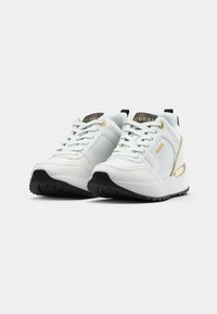 Scarpe da ginnastica bianche con una tomaia in pelle testurizzata, suola in gomma nera, dettagli dorati e una patch con il logo sulla linguetta. Design della punta arrotondata.