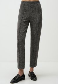 Pantaloni grigi a fantasia con una texture liscia, dotati di una vita alta e design a gamba dritta, abbinati a mocassini neri.