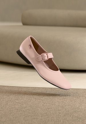 Scarpa bassa Mary Jane in pelle rosa con punta quadrata, cinturino regolabile con fibbia, tacco nero basso e texture liscia, che fluttua sopra un tappeto.