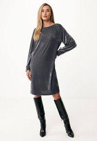 Graues samtweiches Langarmkleid mit Bootsausschnitt, das knapp über dem Knie endet, kombiniert mit schwarzen kniehohen Stiefeletten mit Absatz.