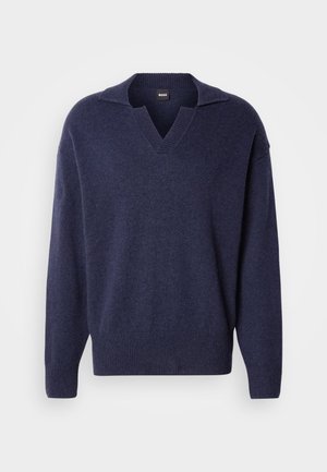 Tumši zils adīts džemperis ar V veida kaklu un apkakli, brīvs piegriezums, ar ribotu aproču un apakšmala. Mīksta tekstūra ar minimālu detalizāciju.