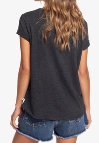 Mørkegrå kortærmet t-shirt med en afslappet pasform, der har rulleærmer og en buet kant, parret med slidte blå denim shorts.