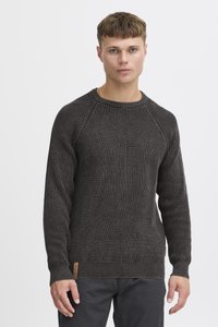 Strikket sort sweater med et struktureret mønster, ribbede manchetter og liv; har et logomærke nederst til venstre.