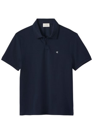 Pomorsko plava polo majica kratkih rukava s ovratnikom, dvostrukim kopčanjem i malim bijelim "cK" logotipom na lijevoj strani prsa.