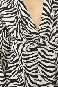Zebra-kuvioinen kietaisumekko, jossa on syvä V-pääntie, solmittu vyötärö ja virtaava kangas vastakkaisissa mustassa ja valkoisessa värissä.
