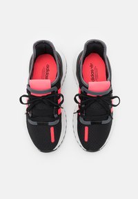 Par de zapatillas de correr Adidas negras con plantillas y detalles en rosa brillante, cordones negros y suelas blancas, vistas desde arriba sobre un fondo blanco.