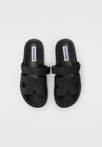Mustad mustad sandaalid sileda nahkviimistlusega, laiad lõigatud rihmad ja pehme sisetald. Lood on tasased ja laiad.