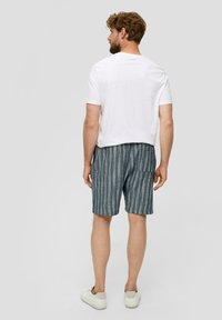 Weißes T-Shirt kombiniert mit blauen gestreiften Shorts aus leichtem Stoff; die Shorts verfügen über eine Gesäßtasche und einen elastischen Bund.