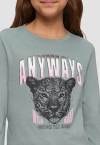 Grijze sweatshirt met een luipaardafbeelding en vetgedrukte tekst "ANYWAYS" in het roze. Het materiaal is zacht en heeft een ontspannen pasvorm en een ronde hals.