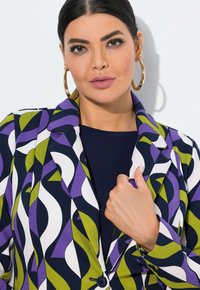 Kolorowa marynarka w geometryczny wzór w odcieniach fioletu, zieleni i bieli, z klapami typu notch i pojedynczym zapięciem na guzik. Gładka tekstura materiału.