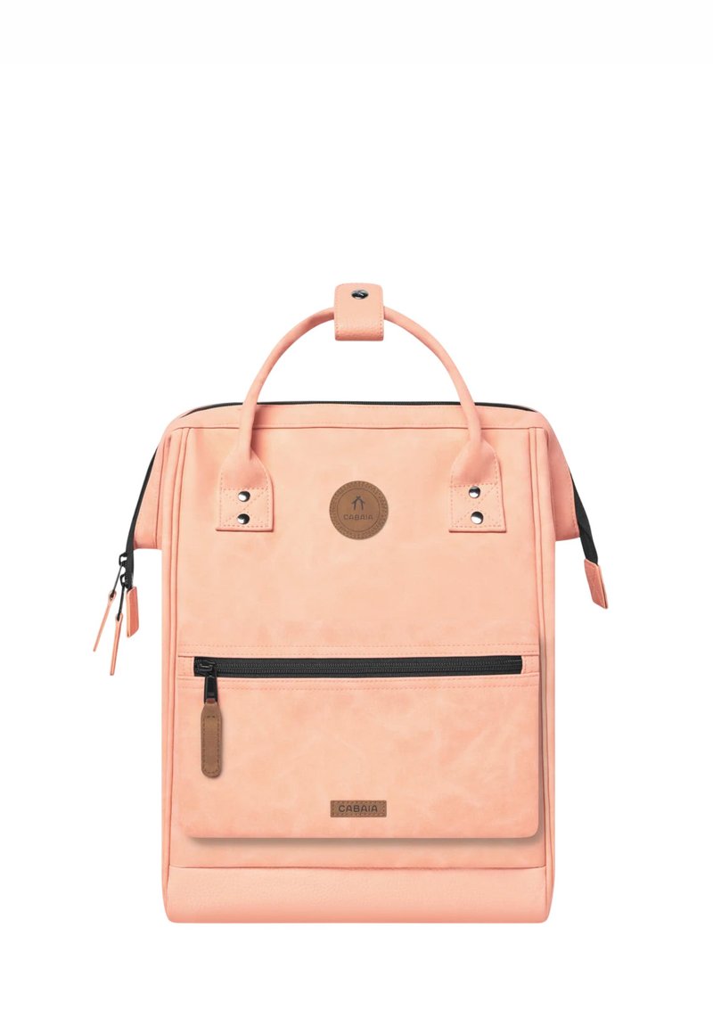 Peach-colored backpack made of soft material features a top handle, front zipper pocket, and a logo patch. Includes accent hardware details.
