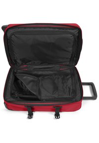 Red wheeled suitcase with black interior, featuring a main compartment, zippered pocket, and adjustable straps. Smooth handle for easy transport.