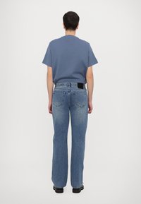 Blue cotton t-shirt with short sleeves paired with faded blue denim jeans. Jeans feature a black label at the back and a straight leg design.