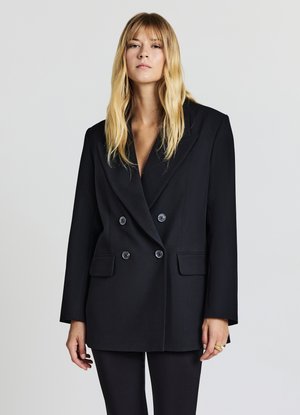 Schwarzer doppelt geknöpfter Blazer, taillierte Passform, breite Rever, zwei Fronttaschen, glatte Textur und große Knöpfe heben sich vor einem hellen Hintergrund ab.