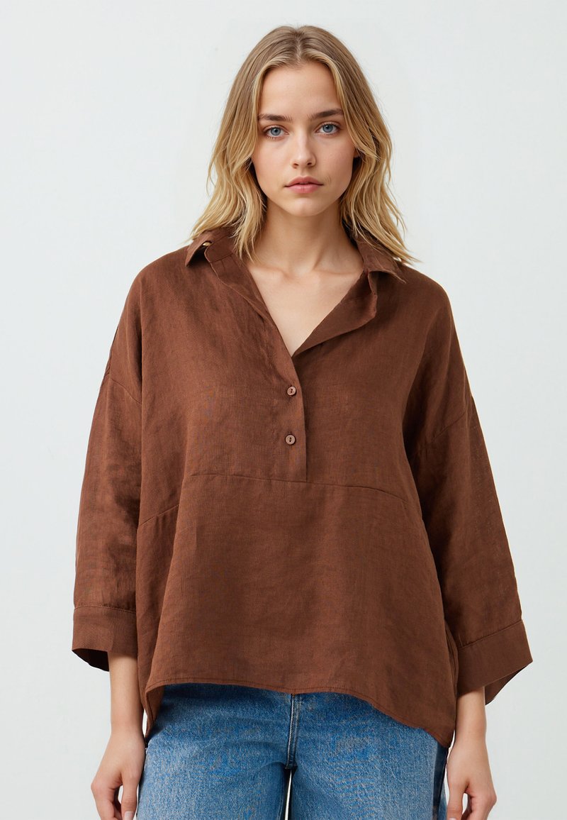 Blusa in lino marrone con colletto, tre bottoni e vestibilità rilassata. Caratterizzata da maniche lunghe e un orlo leggermente curvo.