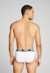 White briefs with a black "PUMA" logo waistband, featuring a smooth texture and fitted design, shown from the back.