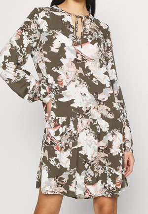 Floral print dress featuring a brown background, with pink and white flowers. Long sleeves, a keyhole neckline with tie detail, and pleated skirt.