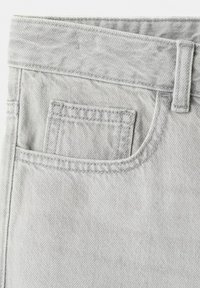Ceinture de jean en denim gris clair avec passants pour ceinture et poche avant comportant une petite poche intérieure pour la monnaie, coutures détaillées visibles.