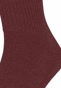 Gros plan sur un tissu tricoté bordeaux à côtes, montrant la texture et le motif détaillés des points sur une surface textile douce.
